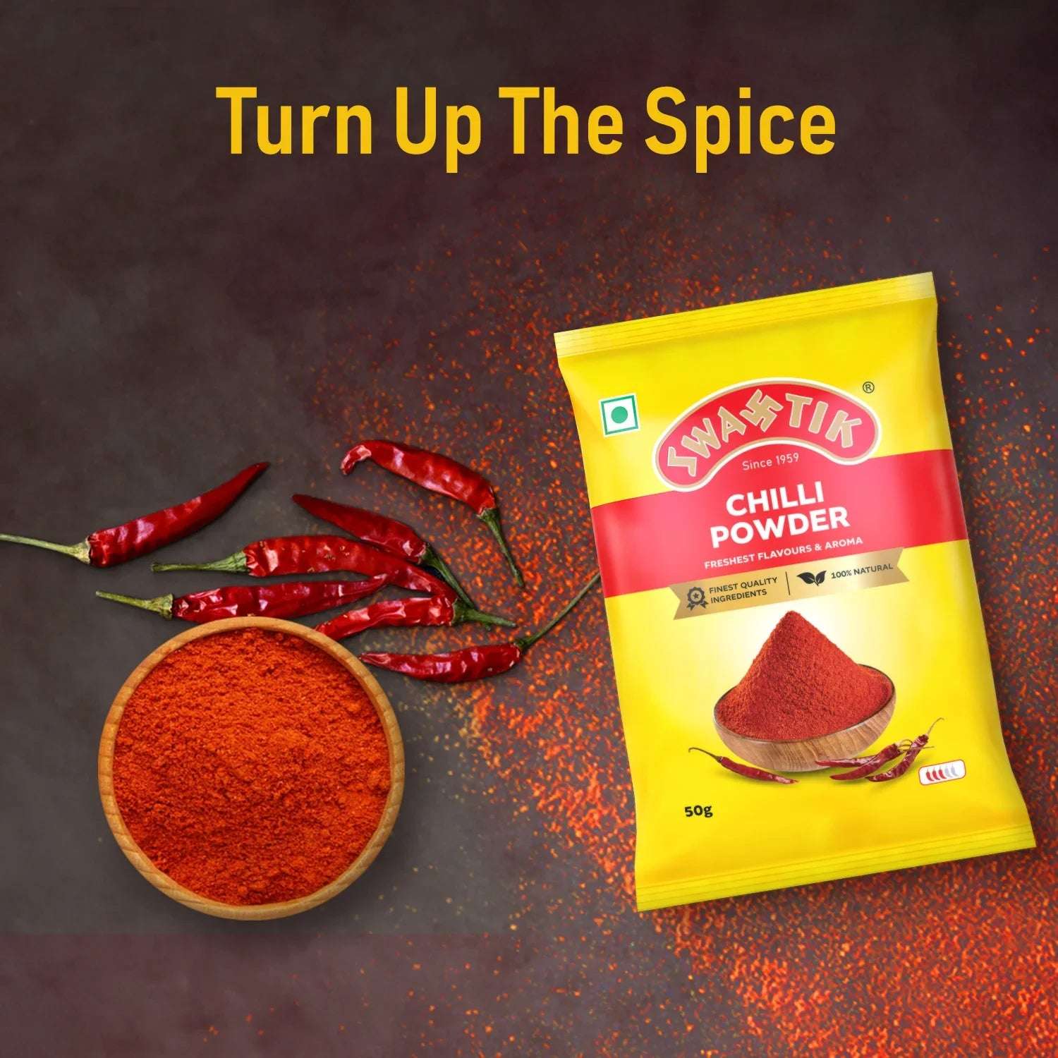 Swastik Chilli Powder 50g pack placed beside dried red chillies and a bowl of ground chilli, with text “Turn Up The Spice” highlighting bold heat and flavour.