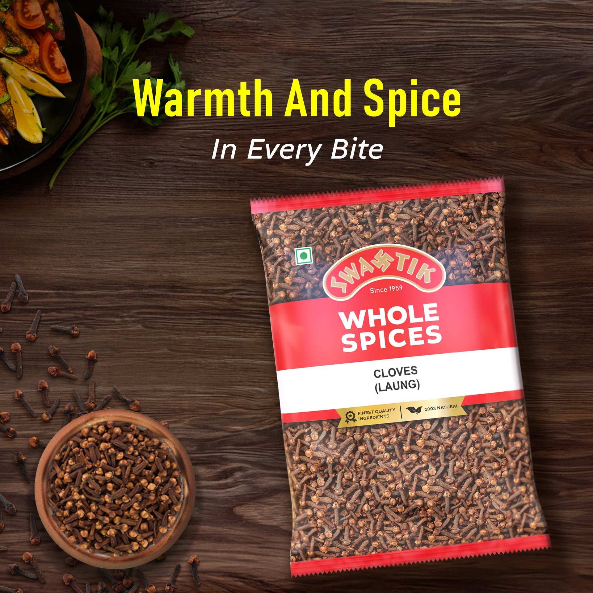 Swastik Clove (Laung) Whole Spices pack placed on a wooden surface with a bowl of cloves and curry, featuring the caption “Warmth and Spice in Every Bite.”